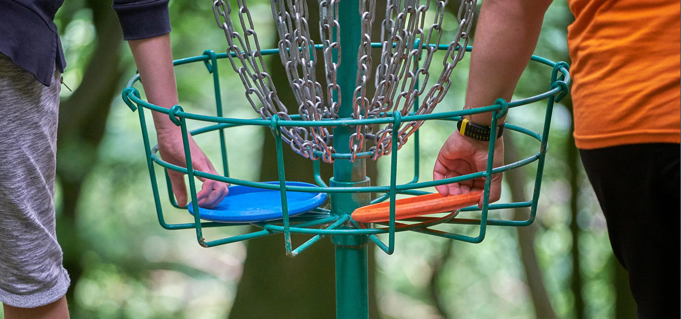 Disc Golfers collecting discs from basket
